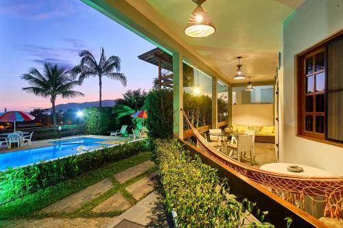 Área de estar com piscina iluminada ao entardecer, rede e varanda acolhedora